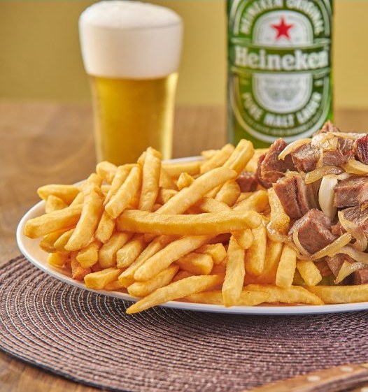 Carne de sol acebolada com batata frita, ao lado de um copo de cerveja gelada.